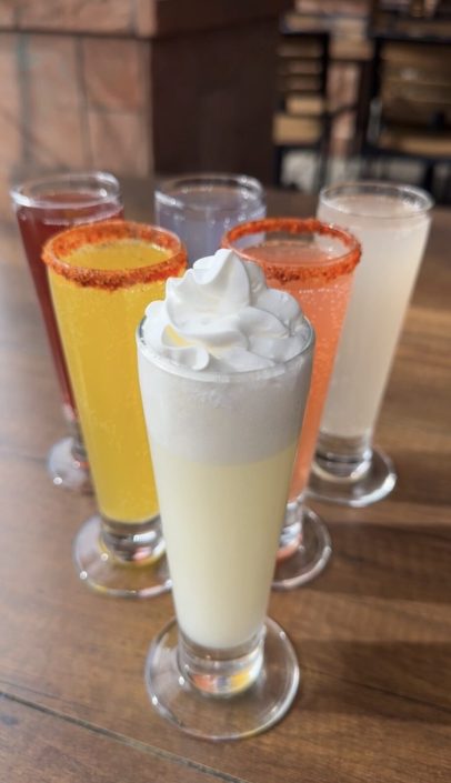 Colorful brunch drinks, one topped with whipped cream