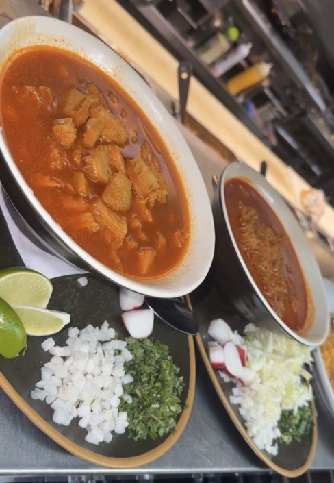 Bowls of menudo with onion, cilantro, radish and lime