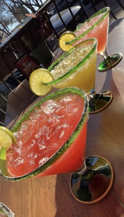 Three margaritas with lime garnish on the patio