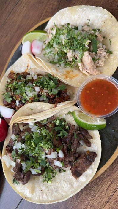 Three street tacos with salsa, lime and radish